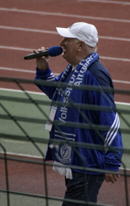 Mann singt mit VSG Altglienicke Schal die Hymne des Vereins